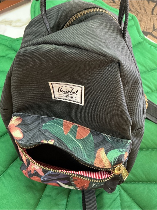 Herschel mini backpack, black with front floral pocket. Double straps at top.